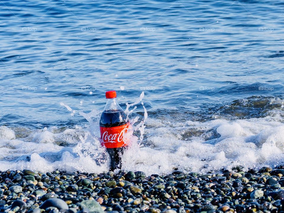 Cola splash on ocean shore