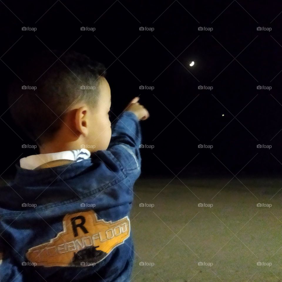 a young boy looking at the moon.