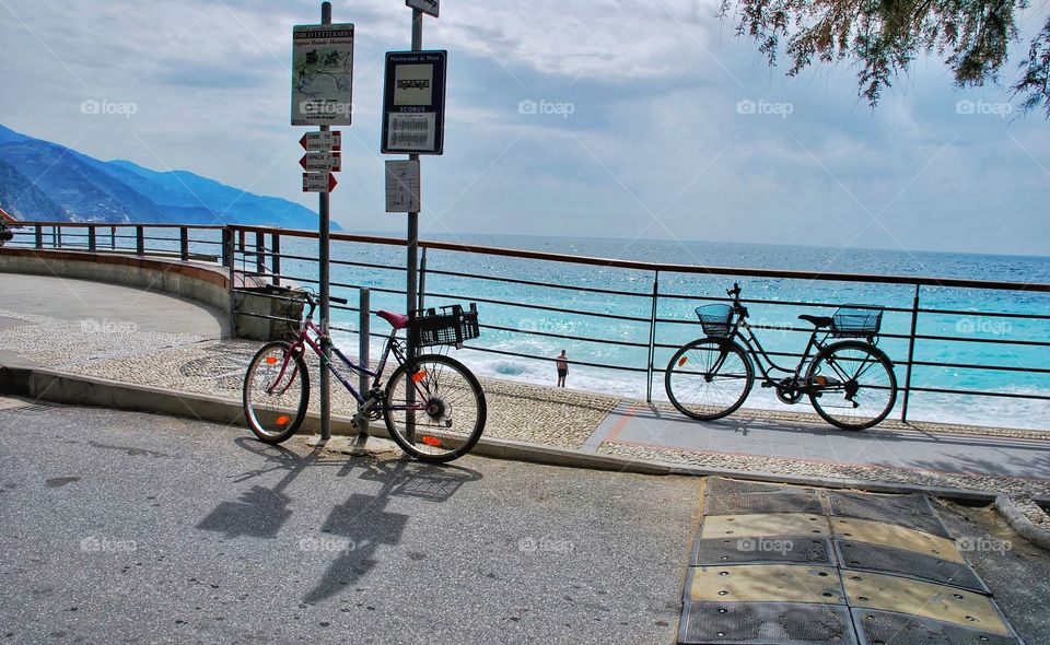 Pair of bikes. A pair of bikes rest along the railing along a beach