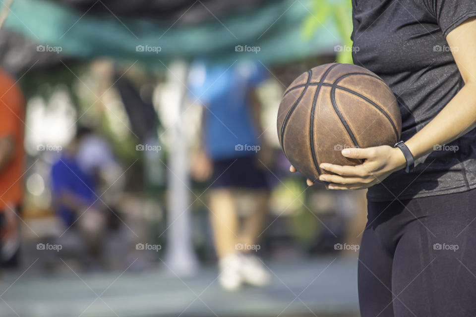 Hand of a woman wearing a watch And holding old basketball .