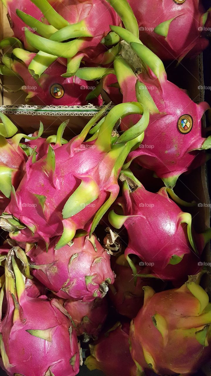 bright pink dragon fruit with green. found in a market in NJ