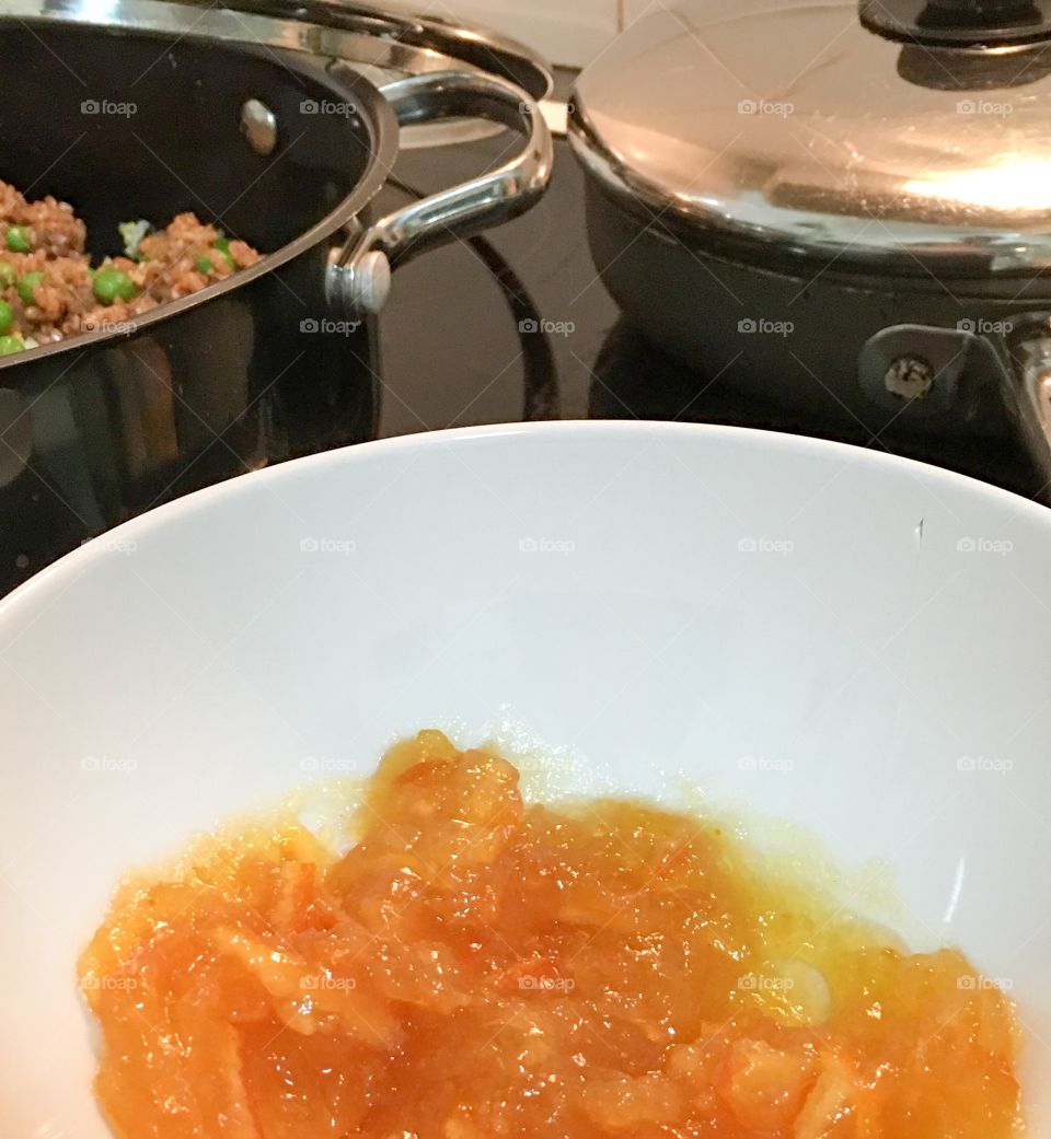 Orange marmalade in white bowl beside stove