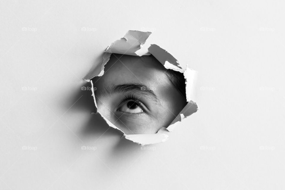 Abstract image of eye in paper hole.