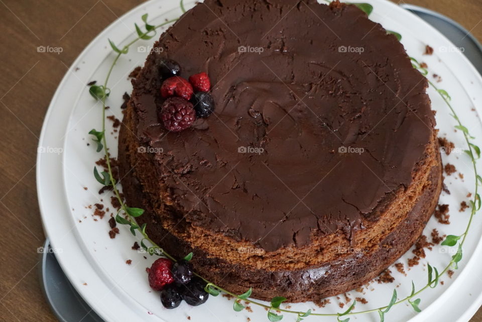 A layered chocolate cake topped with a berry garnish. 