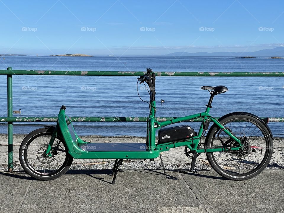 Green bicycle parked by the fence on the beach