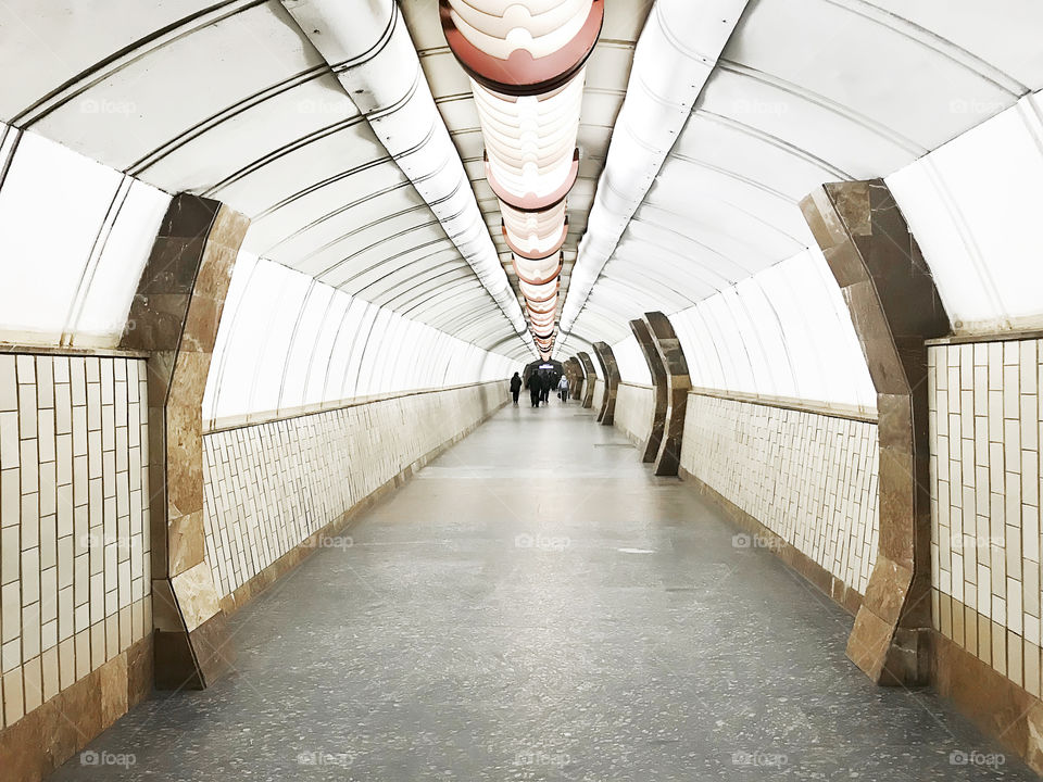 Tiny humans walking through the subway tunnel in the city 