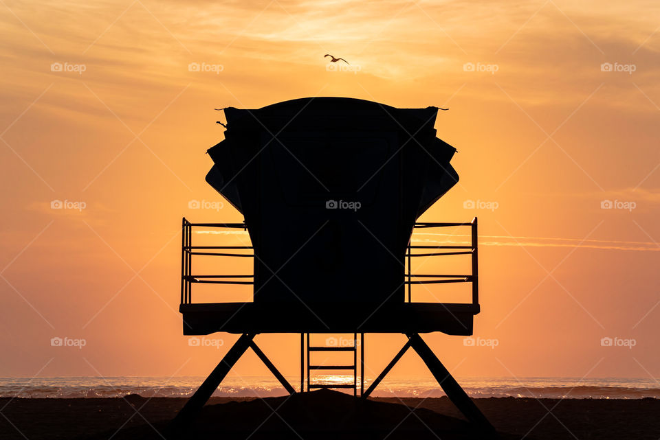 Silhouette of a lifeguard tower in the beach as the sun sets