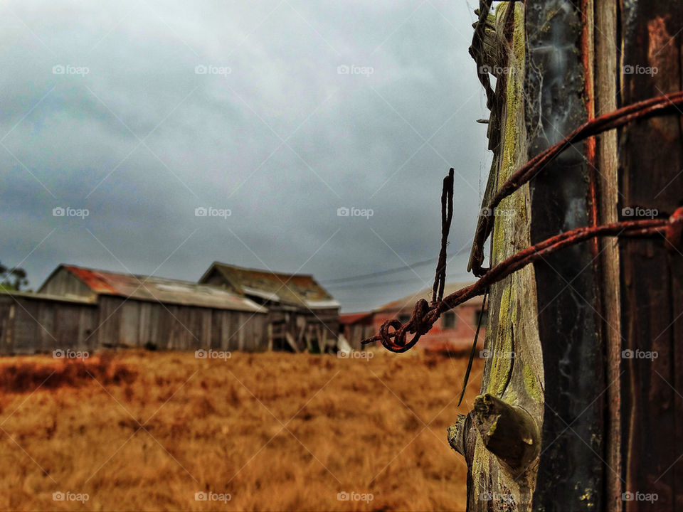 Rusty barbed wire fence post on a crumbling American old west farm