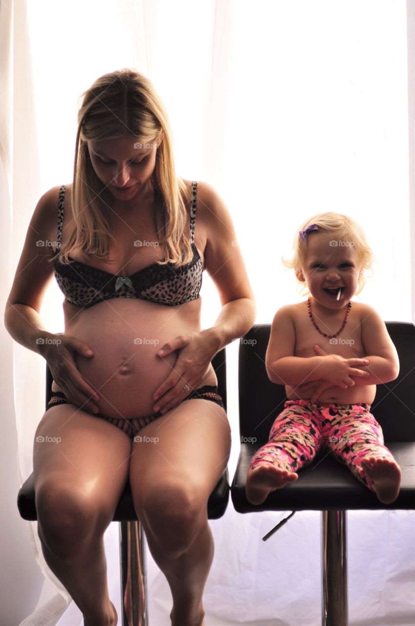 Pregnant woman sitting on chair with her daughter
