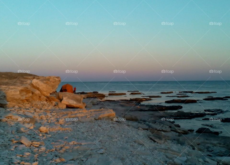 summer wild travel person on a sea stone shore with tent, view from the ground