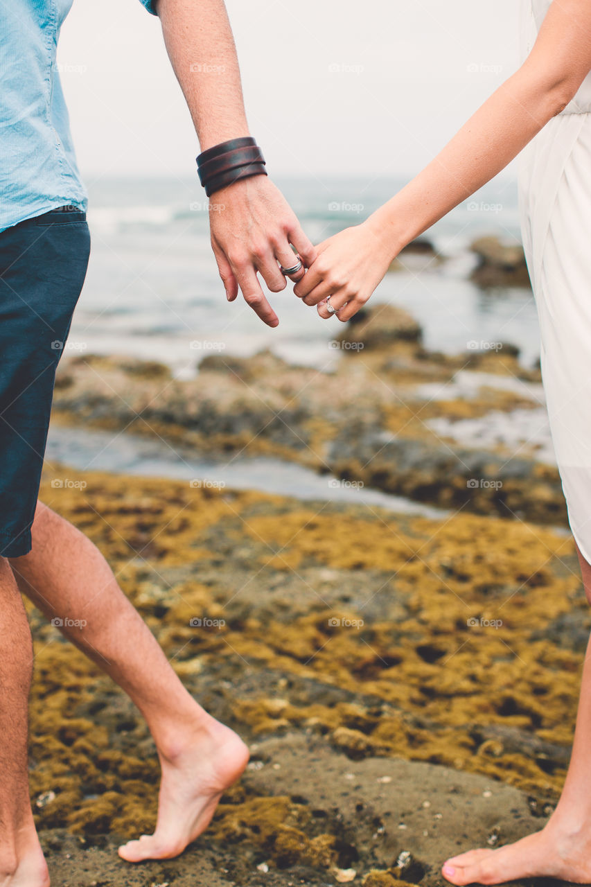 Close-up of couple holding hands at beach