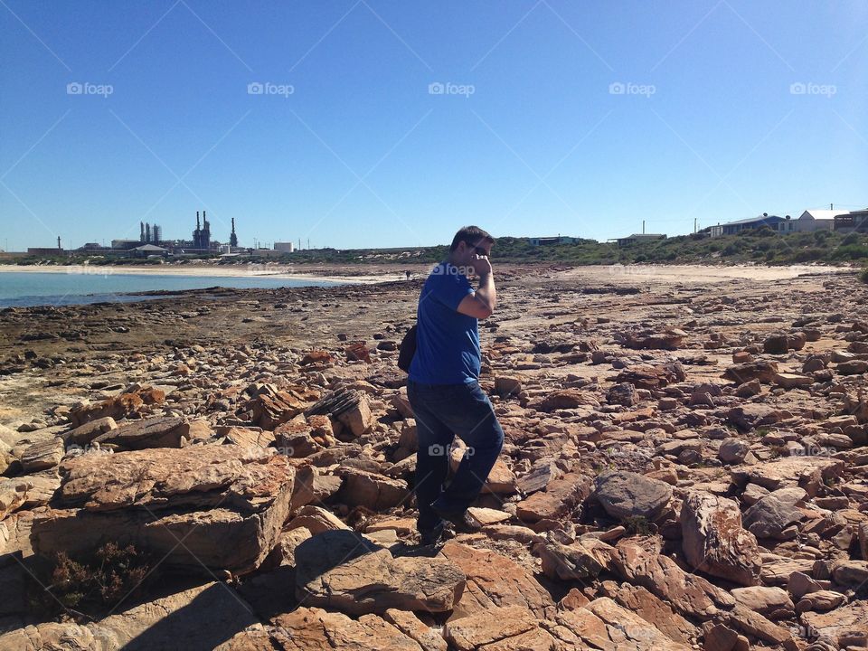 Australia iron ore industry. Young man on beach in foreground, iron ore industry background,?south Australia 