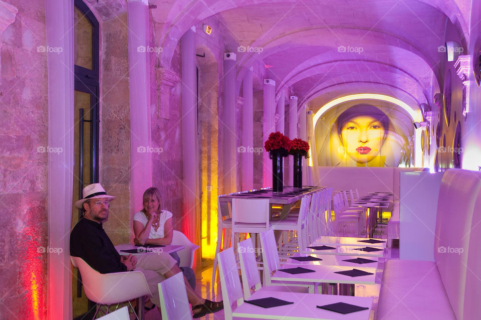 Man and woman seated at a restaurant bathed in purple light in France