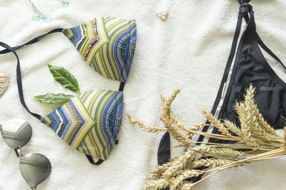 Women's swimsuit with sunglasses on a white towel in the summer season.