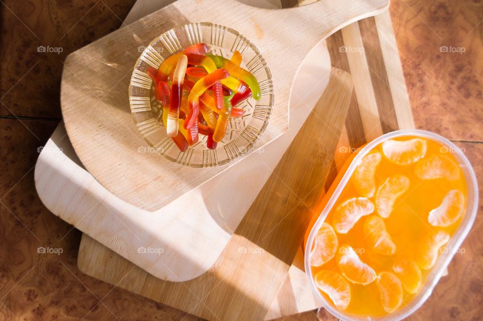 Delicious orange jelly with tangerine slices in a container and jelly worms.