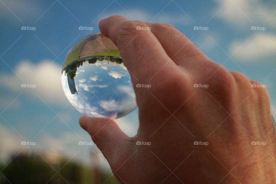 Crystal ball in hand with sky and city reflections