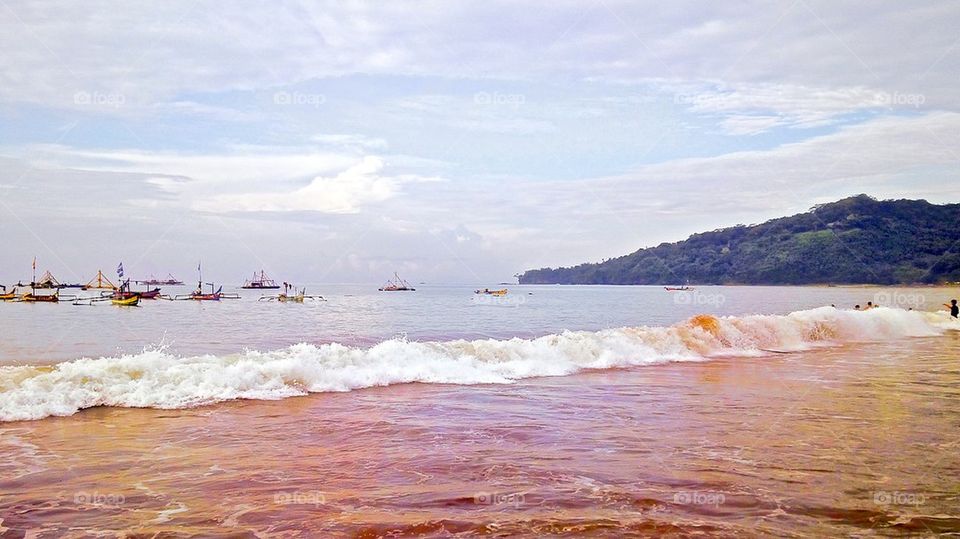 Boats in sea against cloudy sky