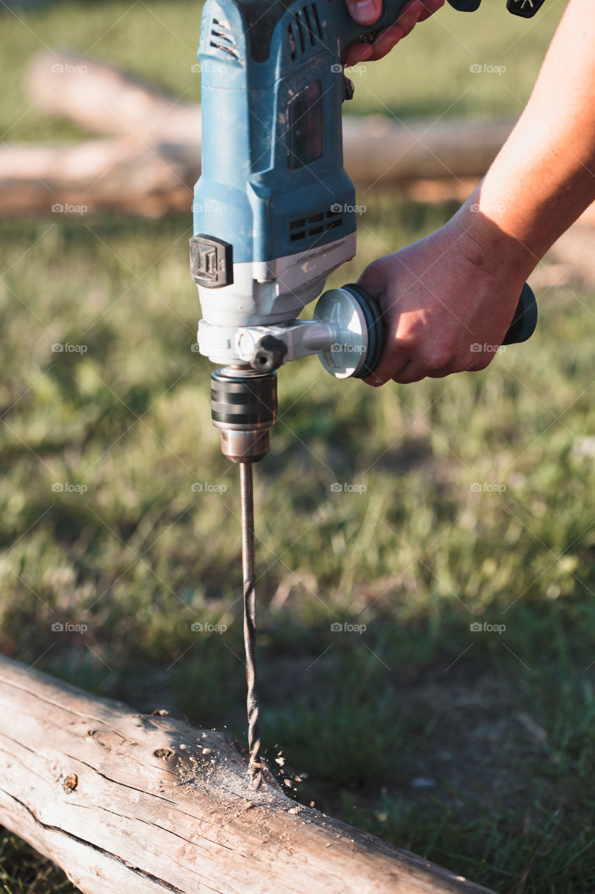 Man drilling hole in timber while working in garden. Real people, authentic situations