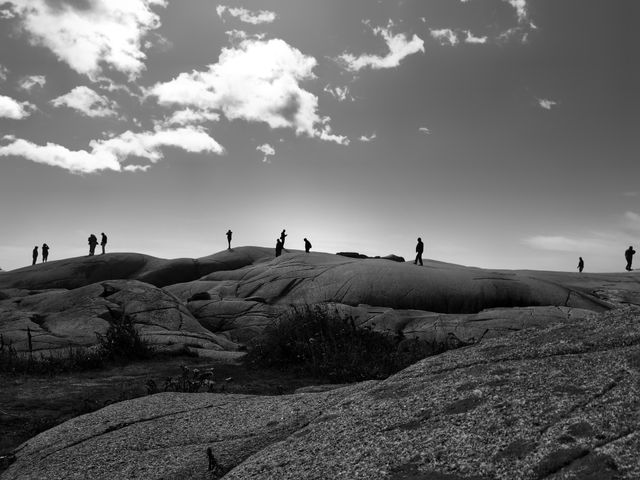 Silhouettes of people wandering on a rocky hillside 