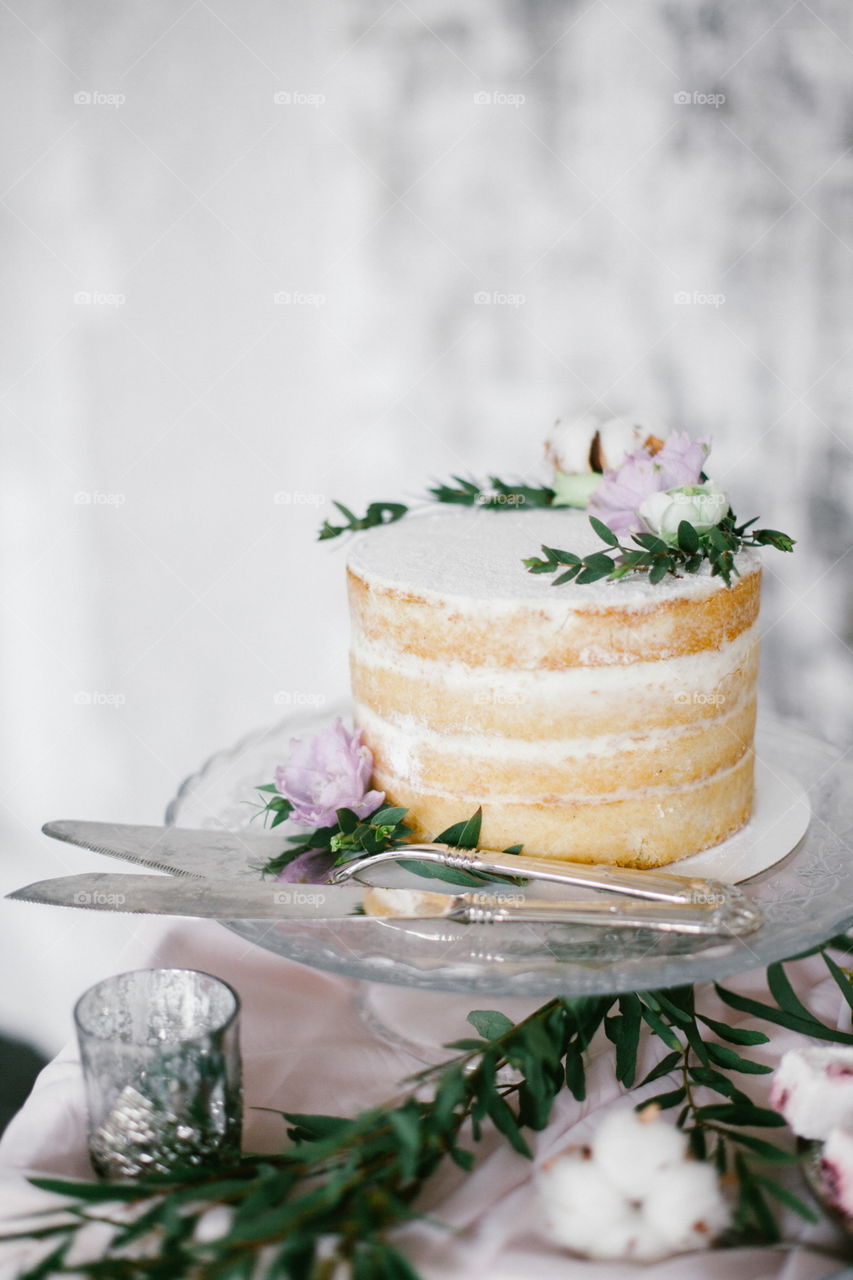 Beautiful wedding round cake with floral decorations on glass cake stand.