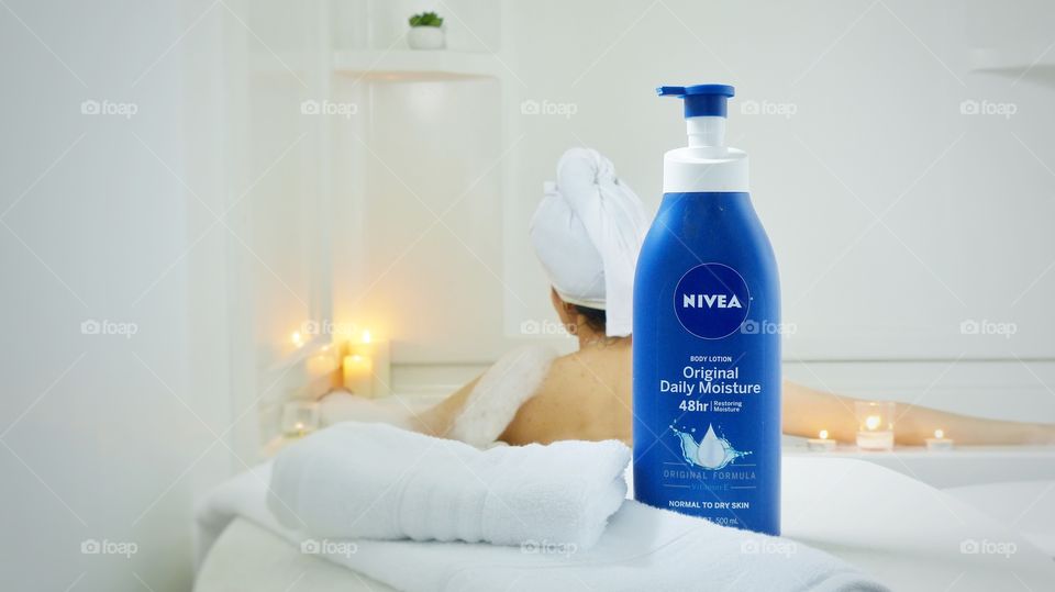 Woman in bathtub with Nivea cream in foreground 