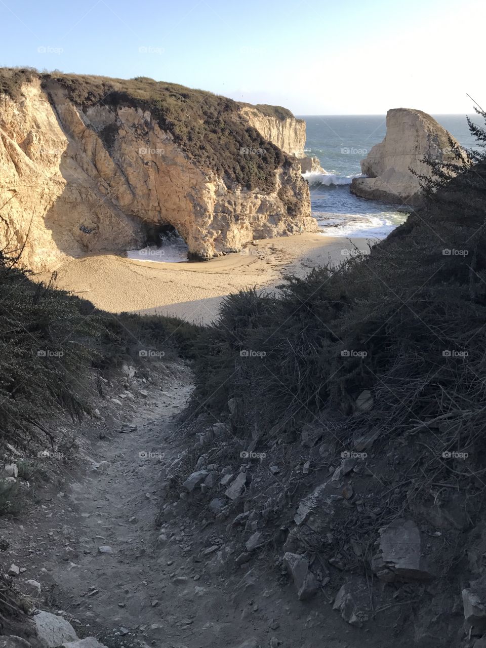 A look down into shark fin cove as the waves crash and the sun sets on this coastal beach. 