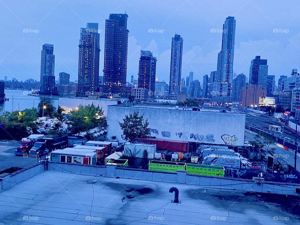 From the “Queens” side staircase of the “Pulaski Bridge” at “Newtown Creek” we overlook LIC skyscrapers and high rises and behind them parts of “Manhattan”. 2023. Hypnotic Productions