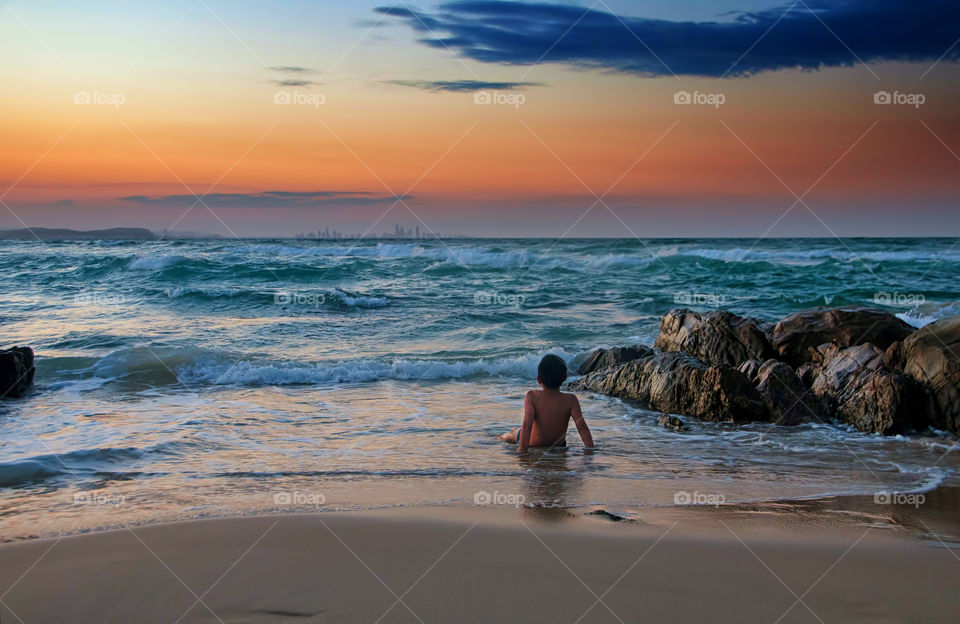 Rear view of boy sitting in beach