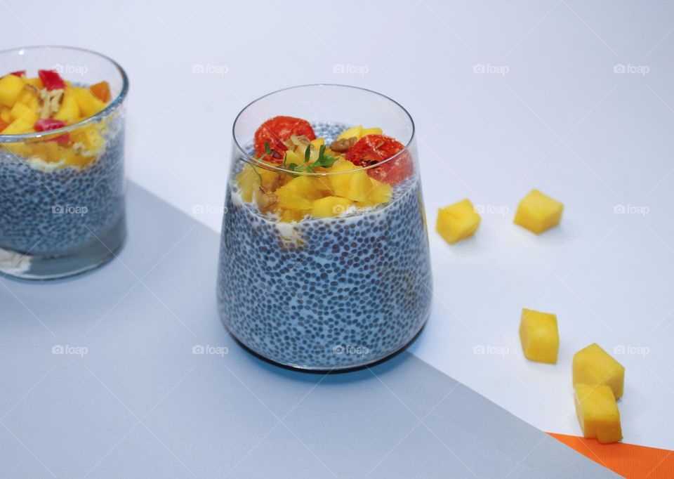 Two glasses of chia pudding with mango on a gray-white background.  Healthy lifestyle