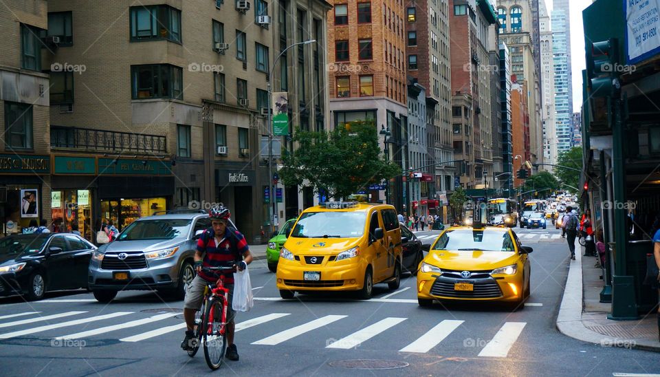 Taxi and biker crossing the street