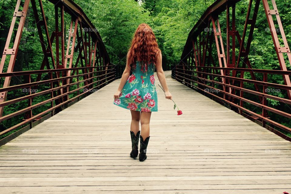 Girl walking on bridge with rose