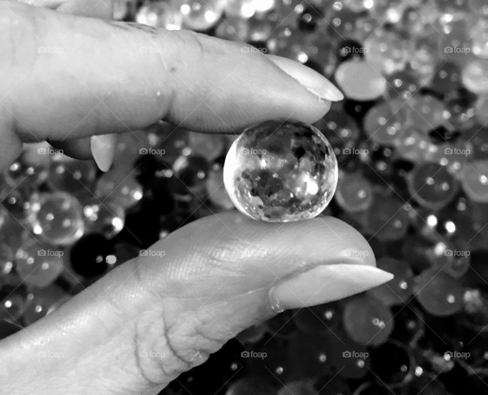Fingers holding tiny crystal ball