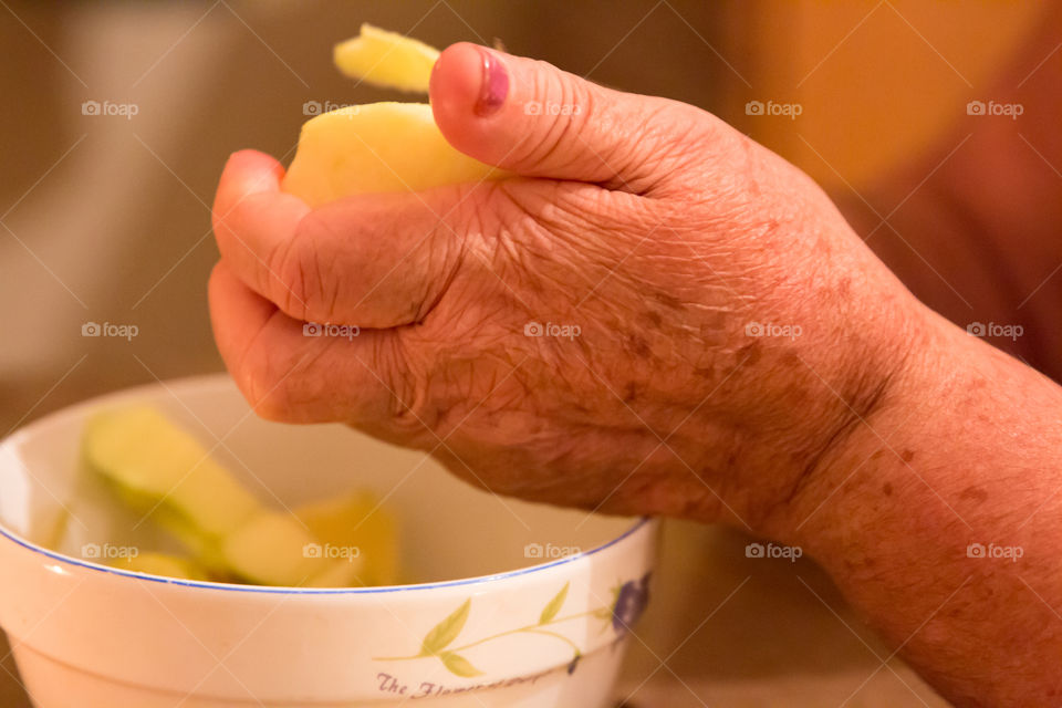 Woman's Aging Hands Peeling A Green Apple
