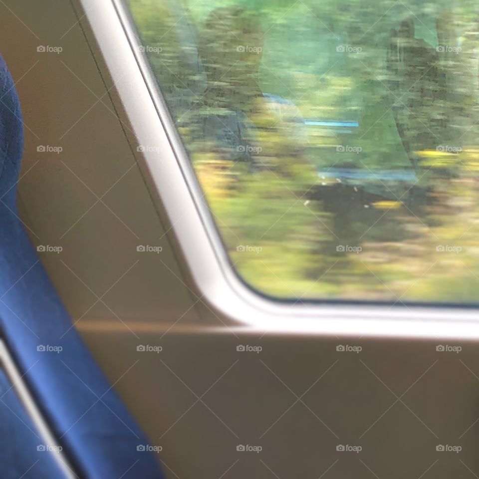 A photo on a window and seat from inside a train while the train are moving. 