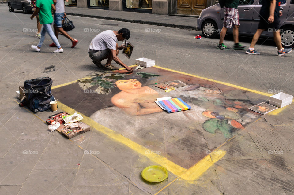 un artista che dipinge Bacco per la strada.
