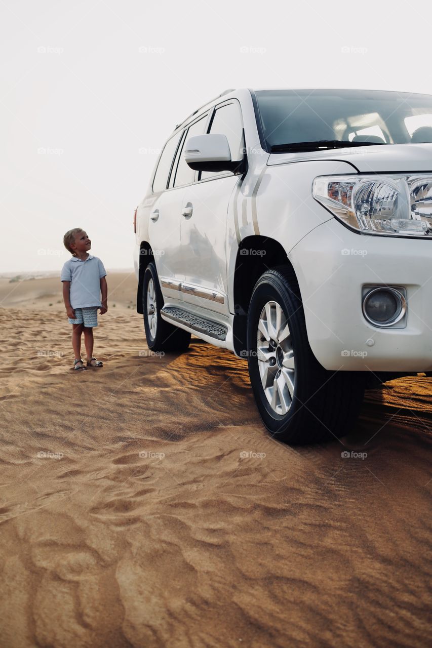 Little boy after driving huge keep car off-road at desert safari sands 