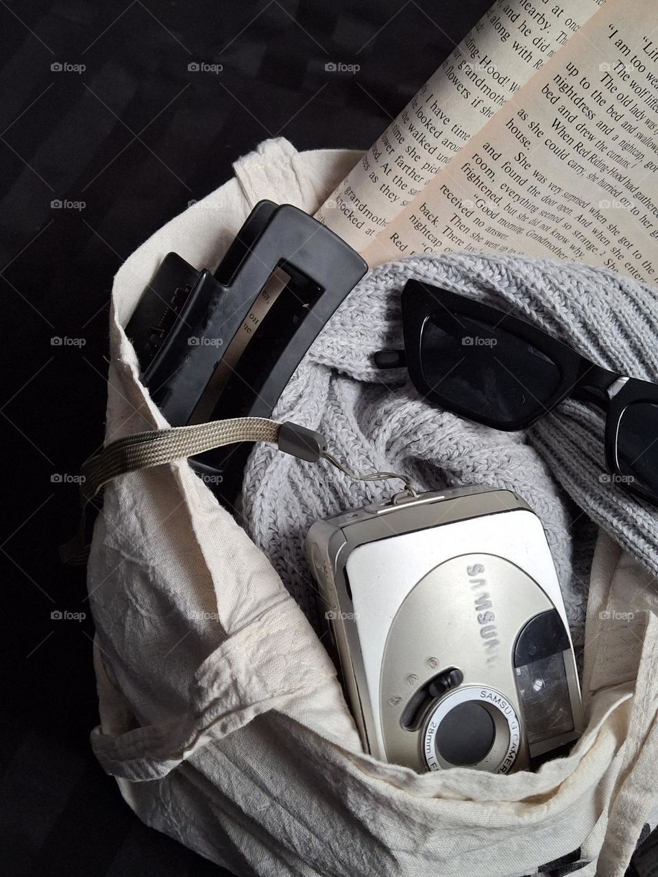 original retro photo with camera, book, glasses and hair clip lying in an eco bag
