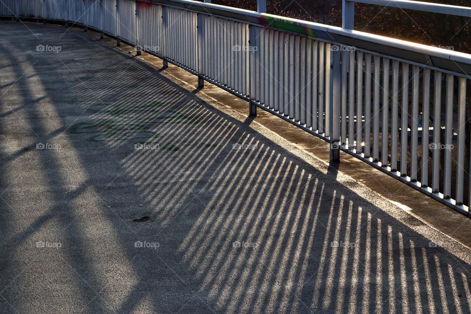 Patterns in the evening light on a bridge with railings in the light and shadows