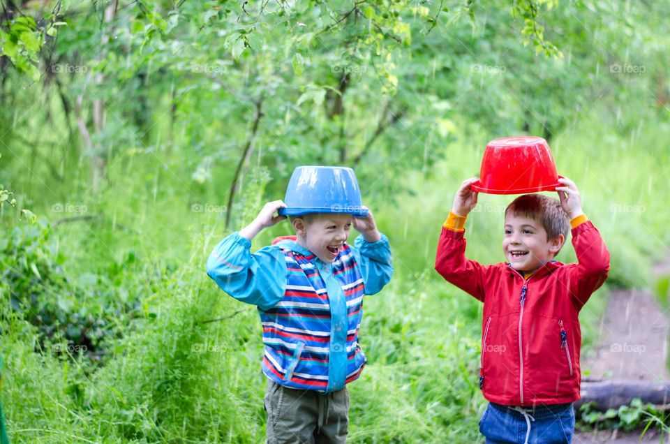 Children Playing in Rainy Spring Day with Buckets on Their Heads