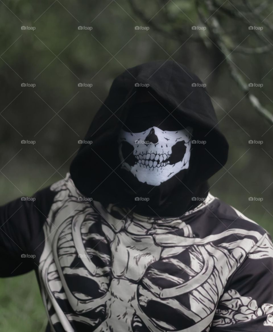 A person dressed as a skeleton, with a hood pulled ominously low over the face