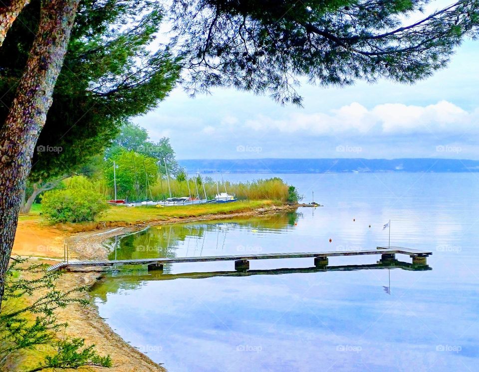 This photo of the Étang de Berre captures a tranquil and picturesque scene. The calm waters of the lagoon reflect the soft blue sky, creating a serene and peaceful atmosphere.