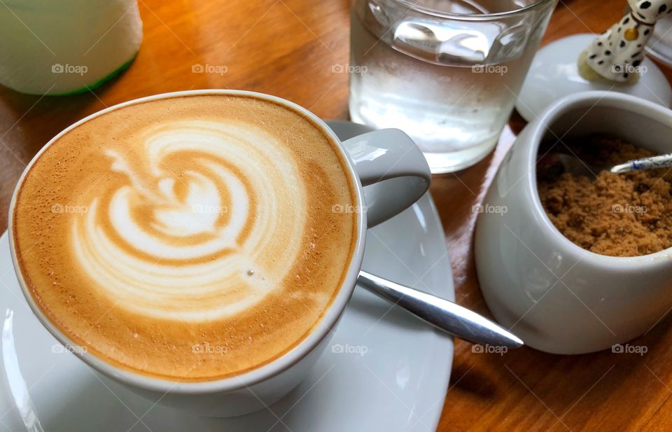 Cup of coffee hot drinks with glass of water on served table ready for breakfast or afternoon break time.