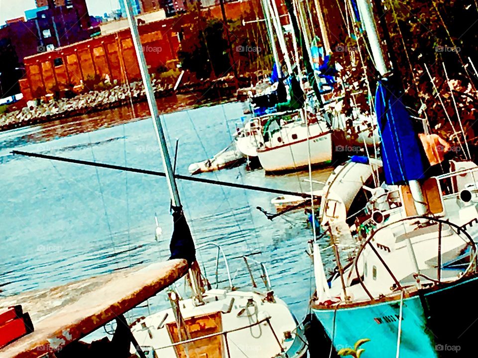 The sailboats of Newtown Creek in Long Island City, Queens, NY in the golden glow of the late afternoon sun with some brownstone buildings at the waterfront in the background. 2021. Hypnotic Productions