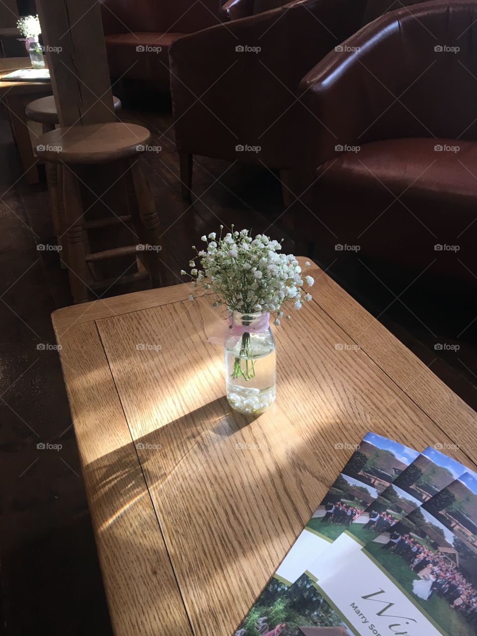 Table at winters barns by the bar with jar of gypsophila and ribbon, and brochure. Wedding venue