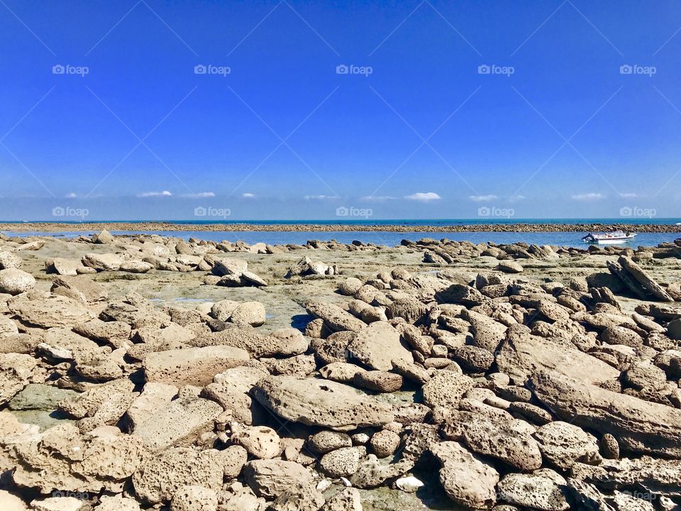 Ebb-tide under A Clear sunny sky, a wonderful natural beauties, valuable coral stones are everywhere besides the seashore. 