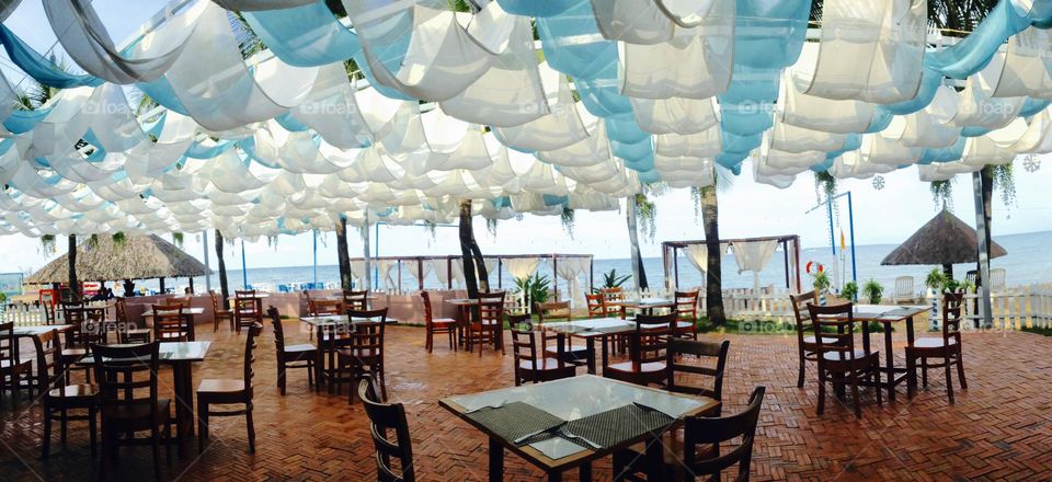 Silk fabrics in the wind and tables and chairs in a restaurant facing the sea