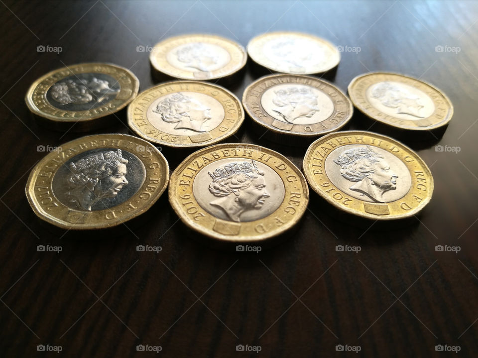 1 pound coins on wood table with copy space at the bottom.