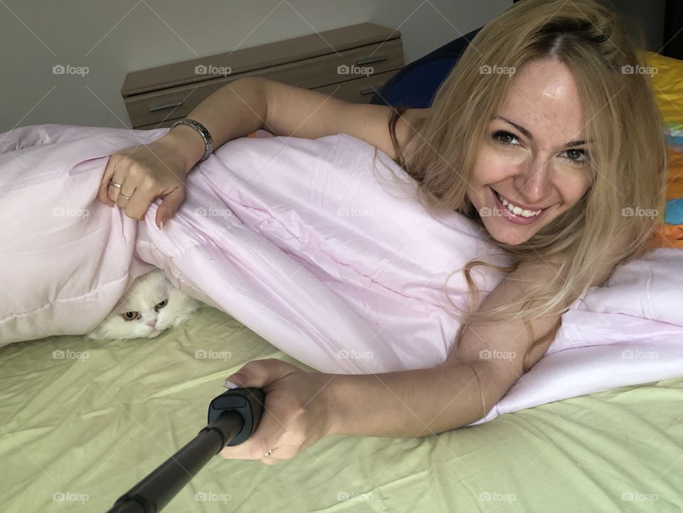 Young woman and cute kitty under duvet