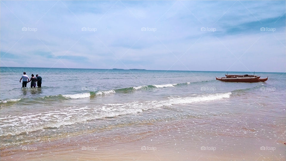 three persons at the beach with a boat in a right side